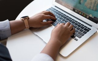 Dark-skinned hands resting on a laptop keyboard. By Christina @ wocintechchat.com